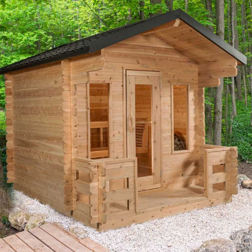 Outdoor cedar Georgian sauna cabin with porch, clear glass door and windows, shown in a wooded backyard for natural relaxation.